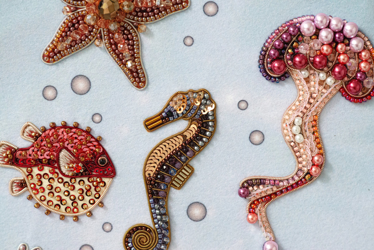 a collection of colorful, intricately designed sea creatures, including a starfish, a seahorse, and a jellyfish, all adorned with beaded and embroidered embellishments.