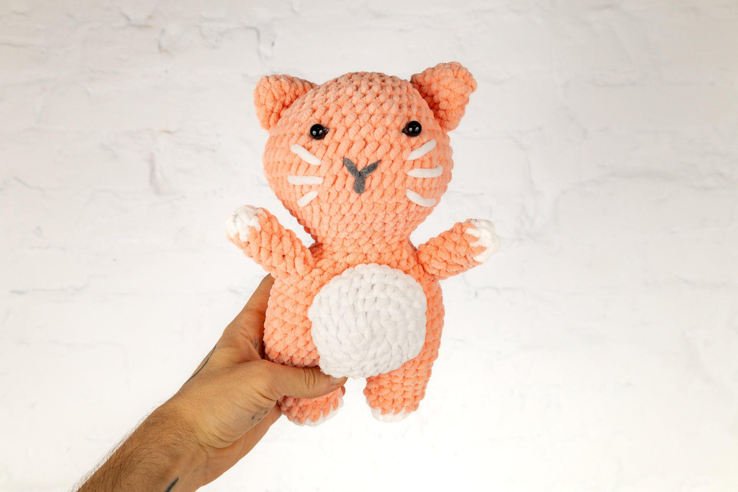 a hand holding a small crocheted stuffed animal
