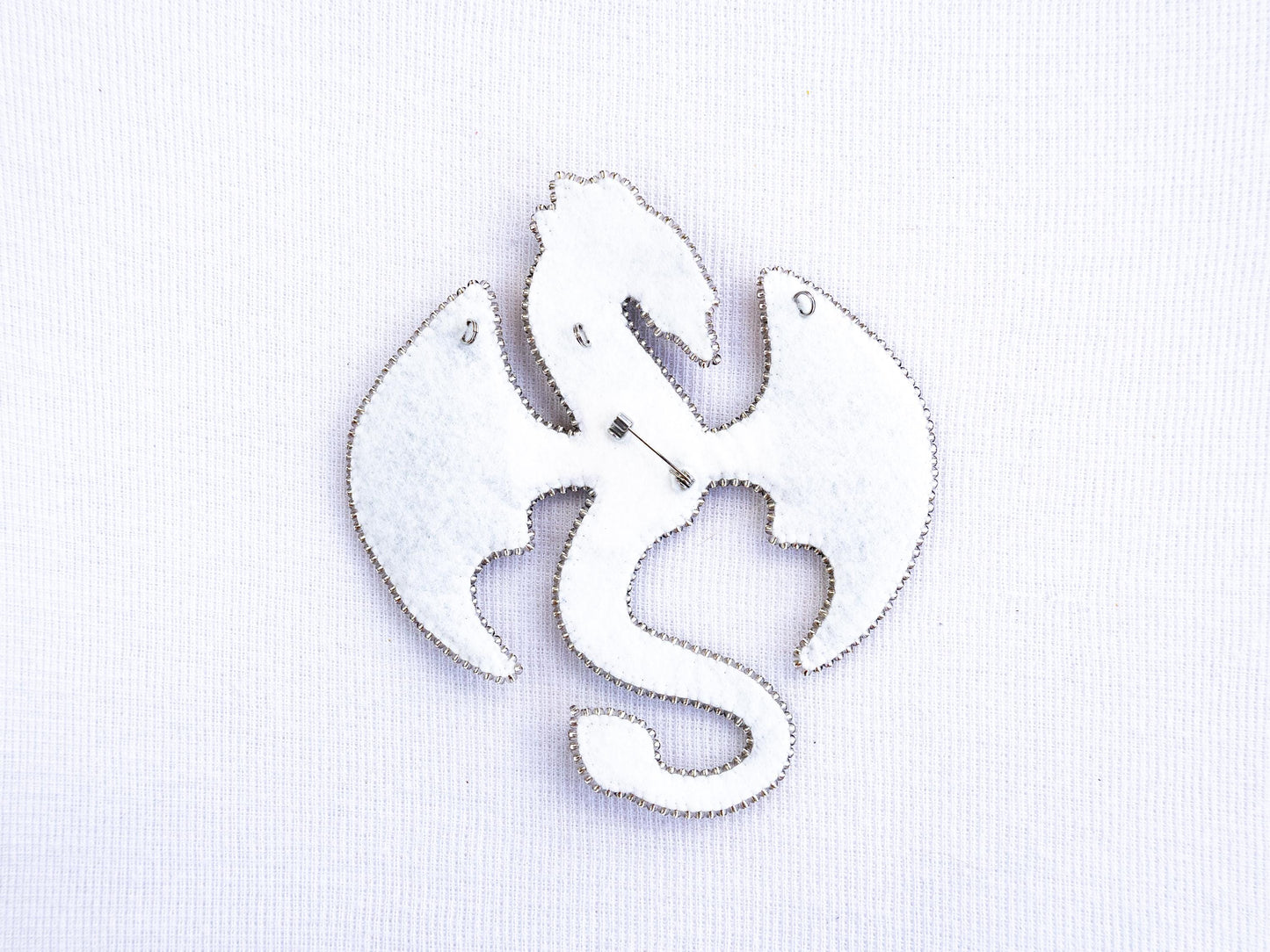 a white brooch with a fish design on it