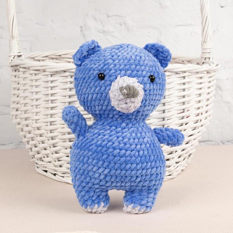 a blue teddy bear sitting next to a ball of yarn