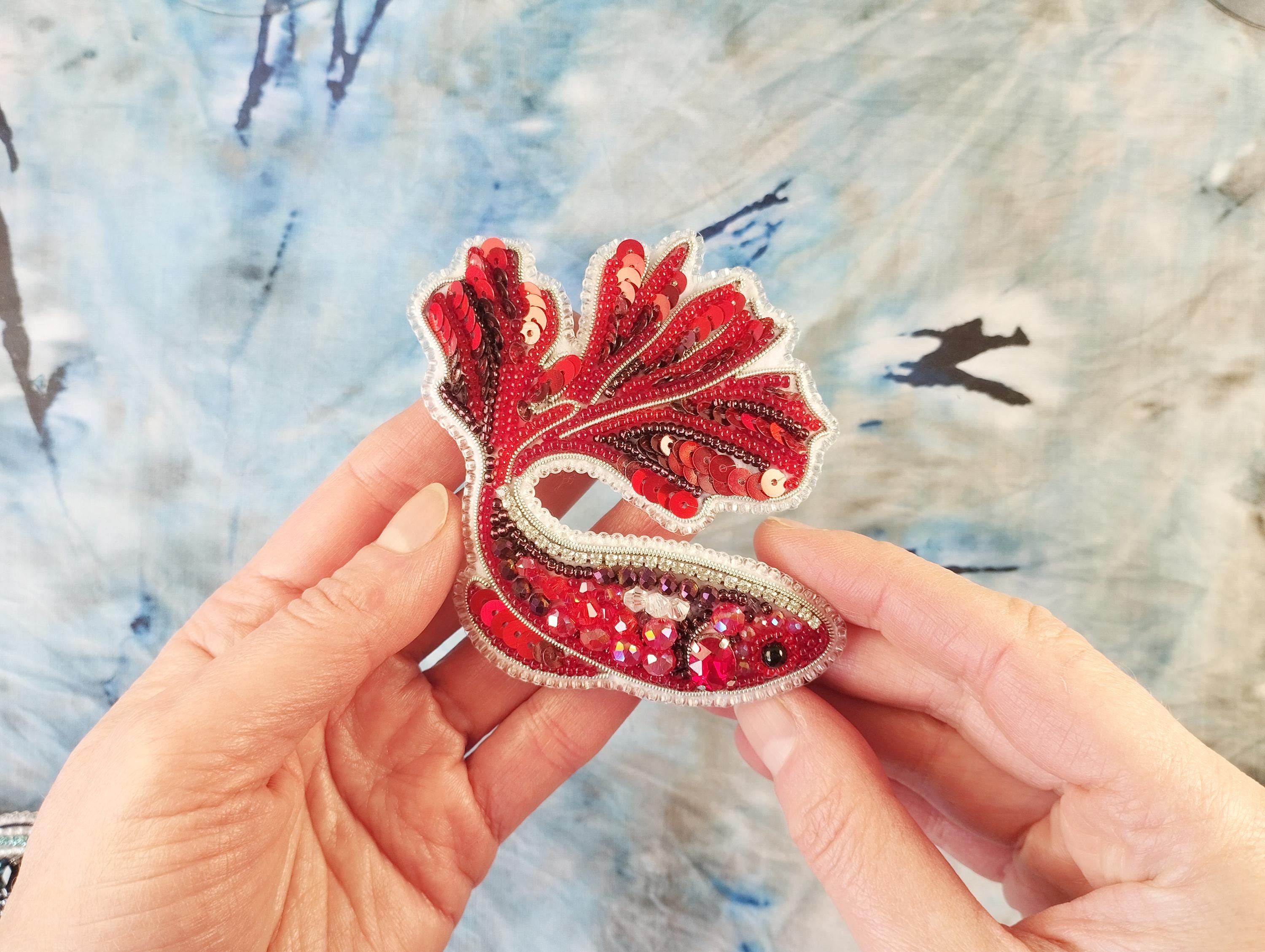 a person is holding a red and white brooch