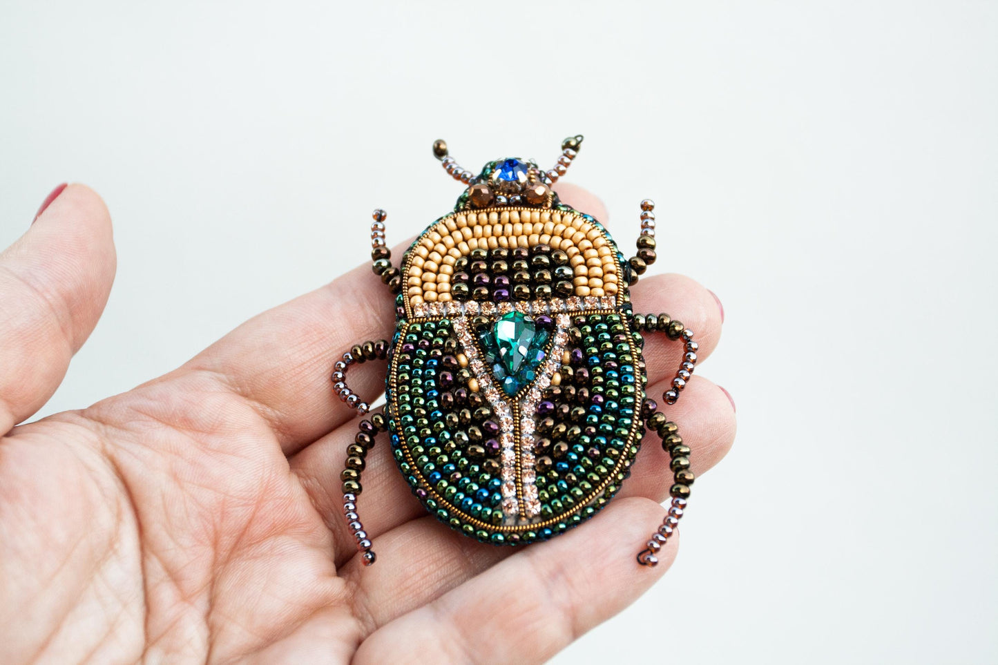 a person holding a beaded beetle in their hand