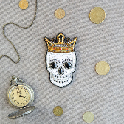a skull with a crown next to a pocket watch