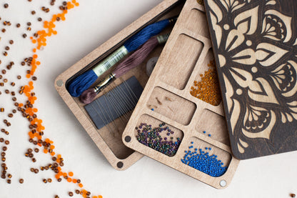 a wooden box filled with beads and thread