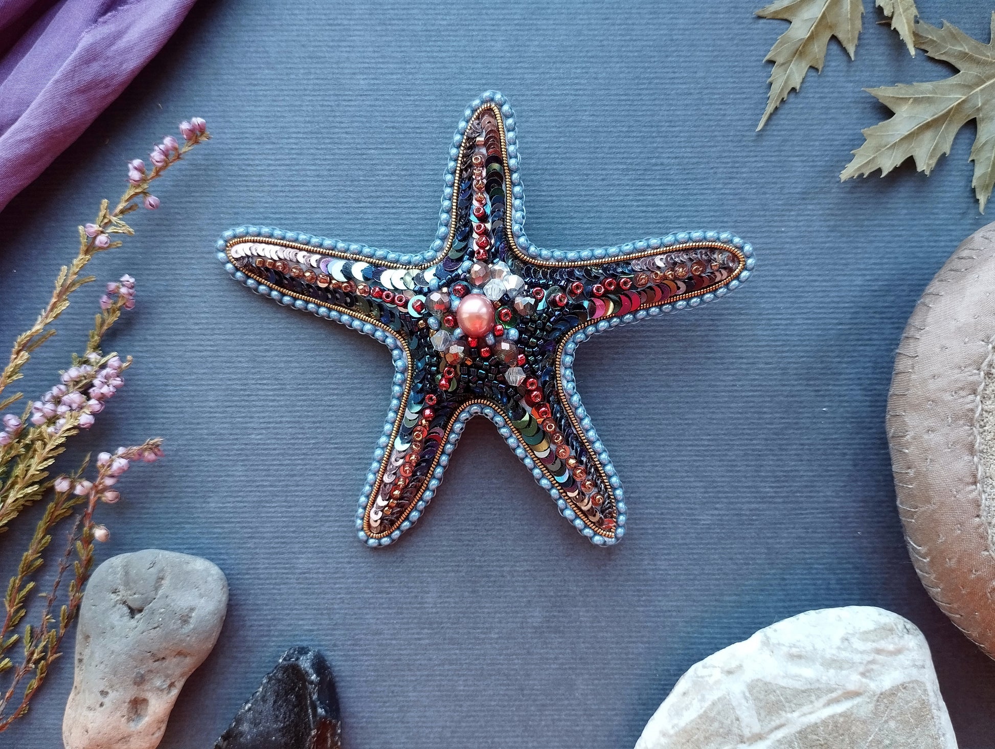 a starfish adorned with colorful beads and pearls, surrounded by various natural elements such as leaves, rocks, and flowers, creating a serene and harmonious composition.