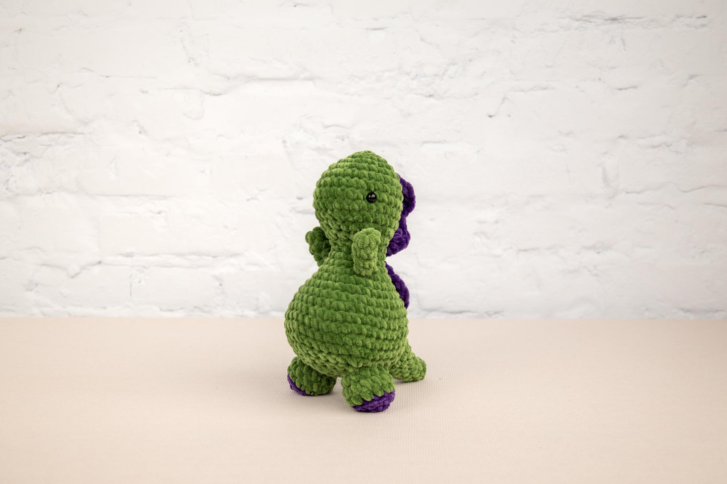 a crocheted green and purple dinosaur sitting on a table