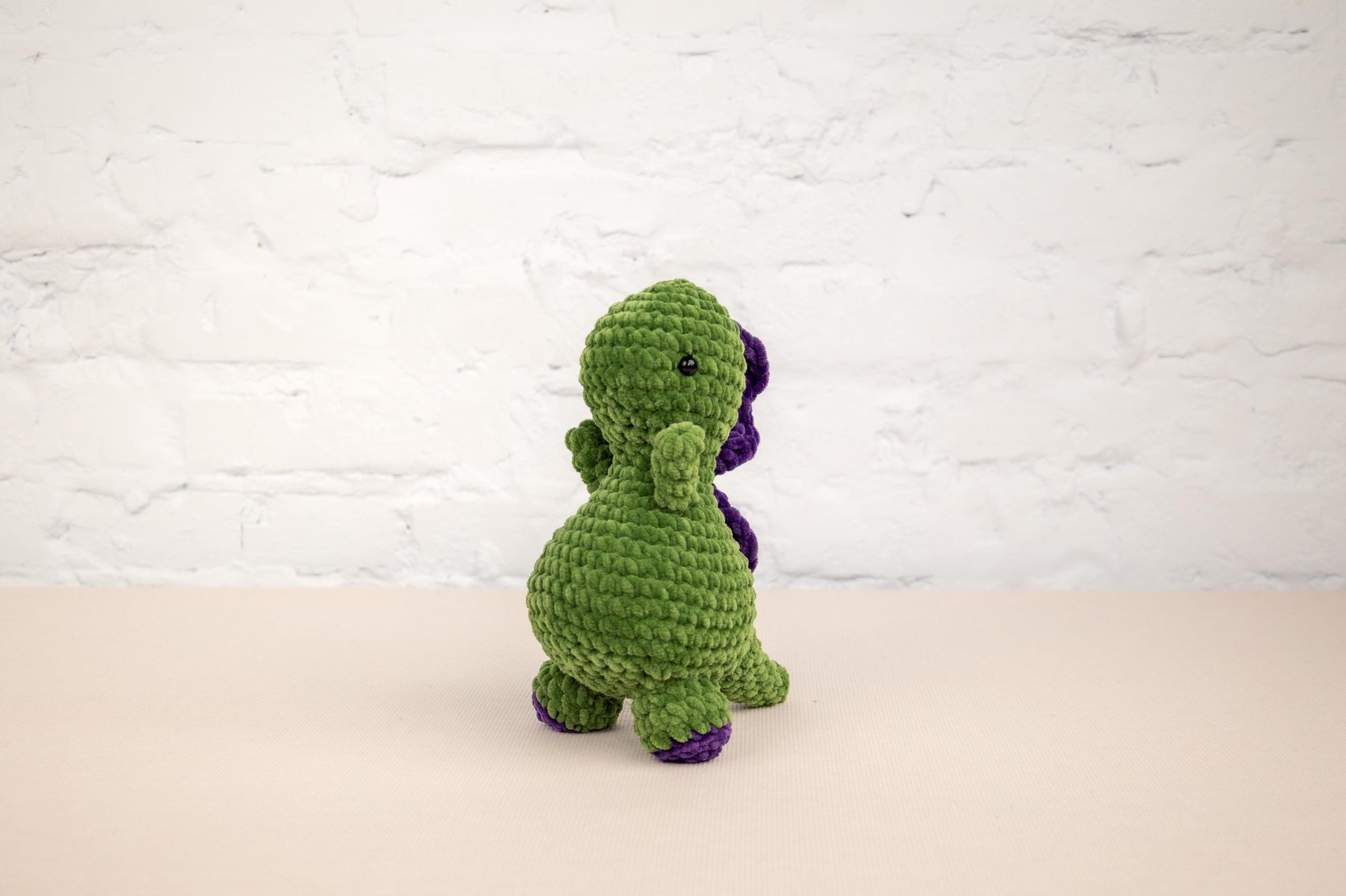 a crocheted green and purple dinosaur sitting on a table