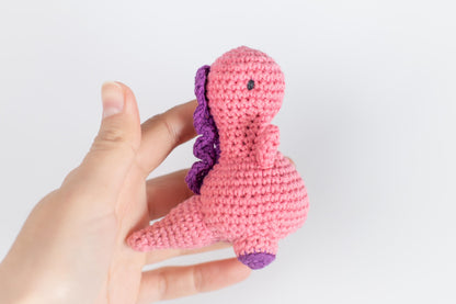 a hand holding a pink crocheted stuffed animal
