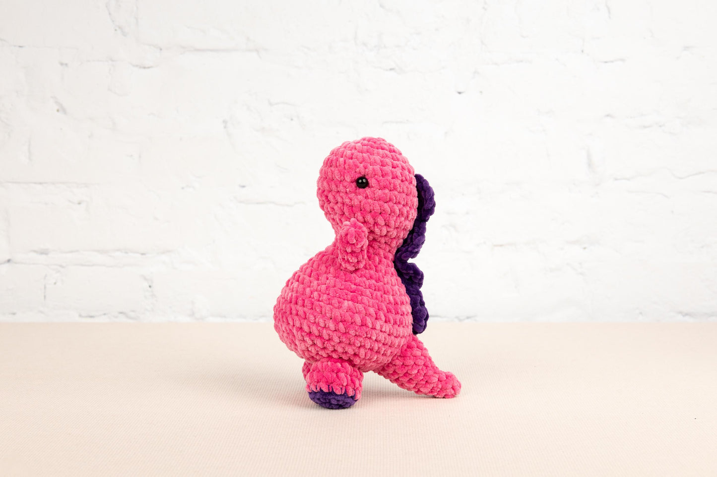 a pink and purple stuffed animal sitting on top of a table