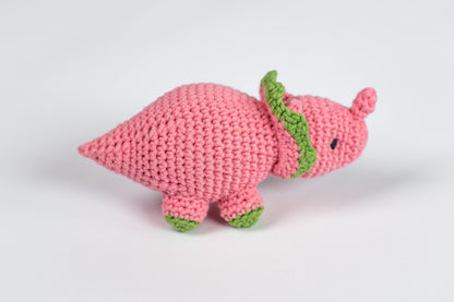 a crocheted pink stuffed animal with a green tail