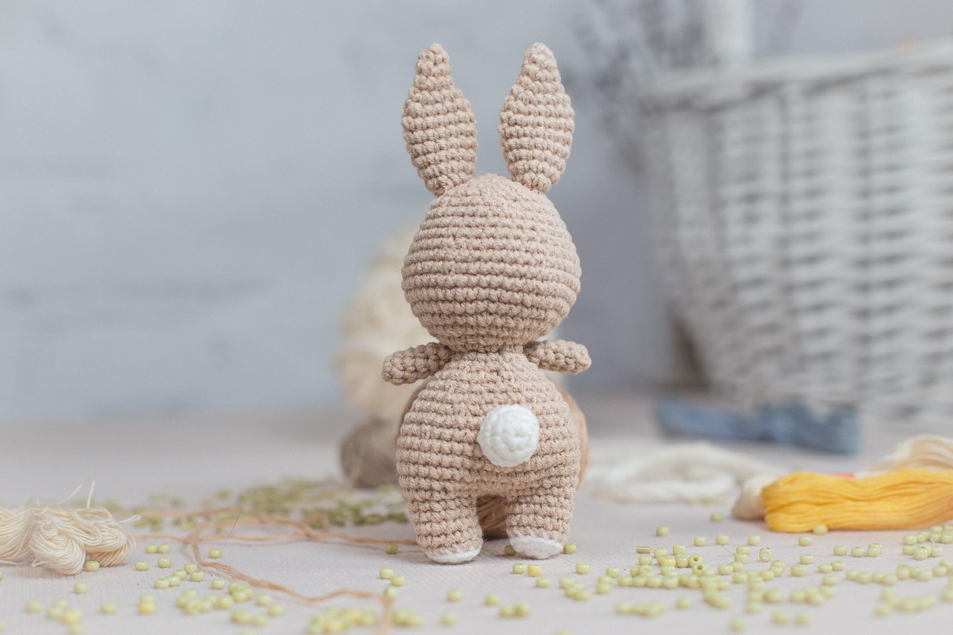 a crocheted bunny standing next to a basket of yarn