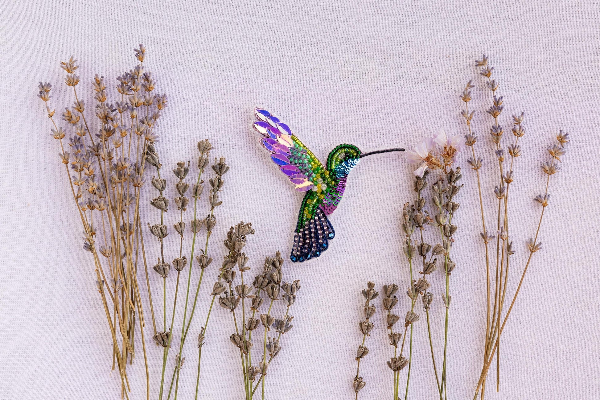 a hummingbird flying over a bunch of lavender flowers