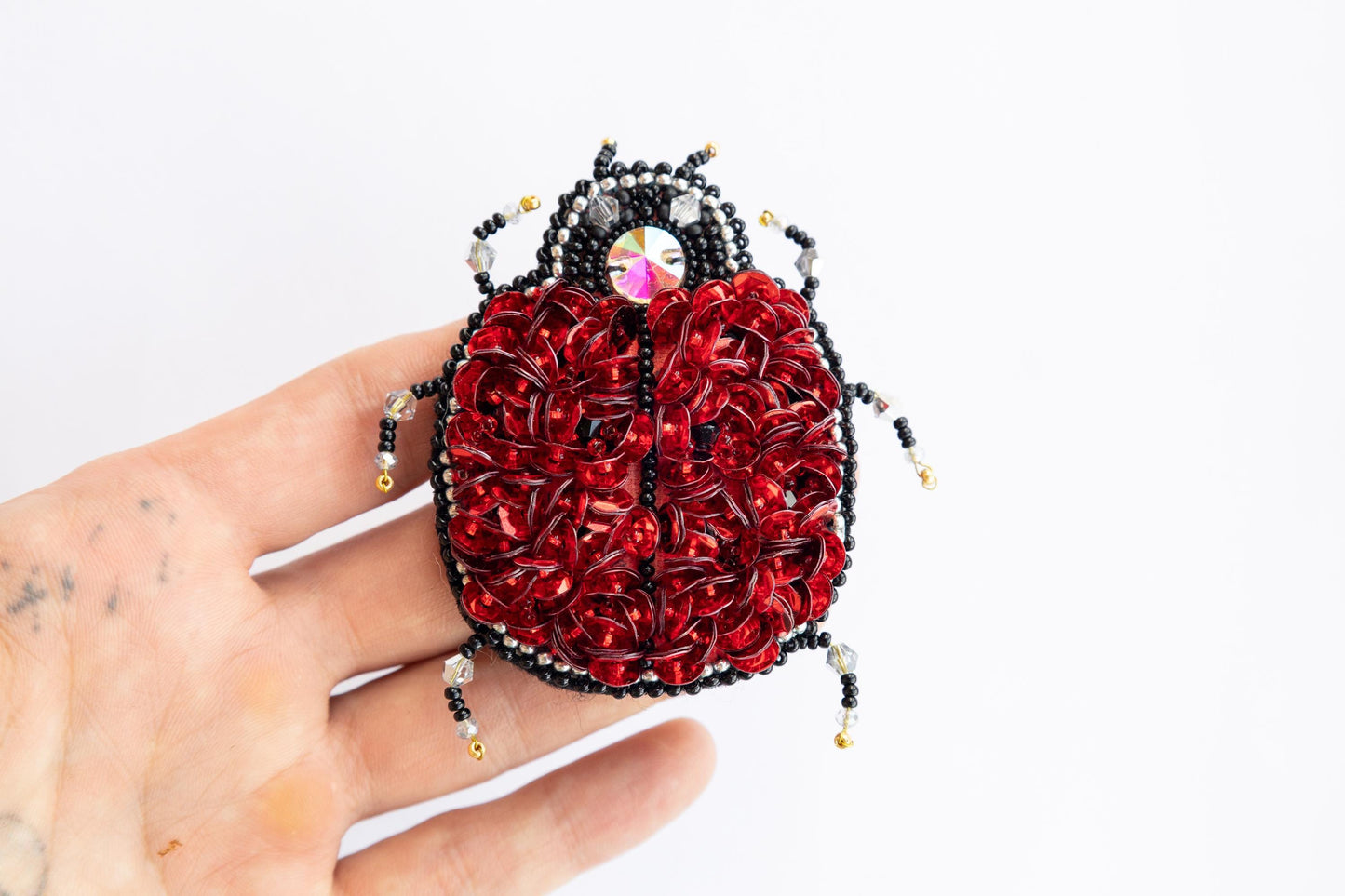 a hand holding a beaded red and black purse