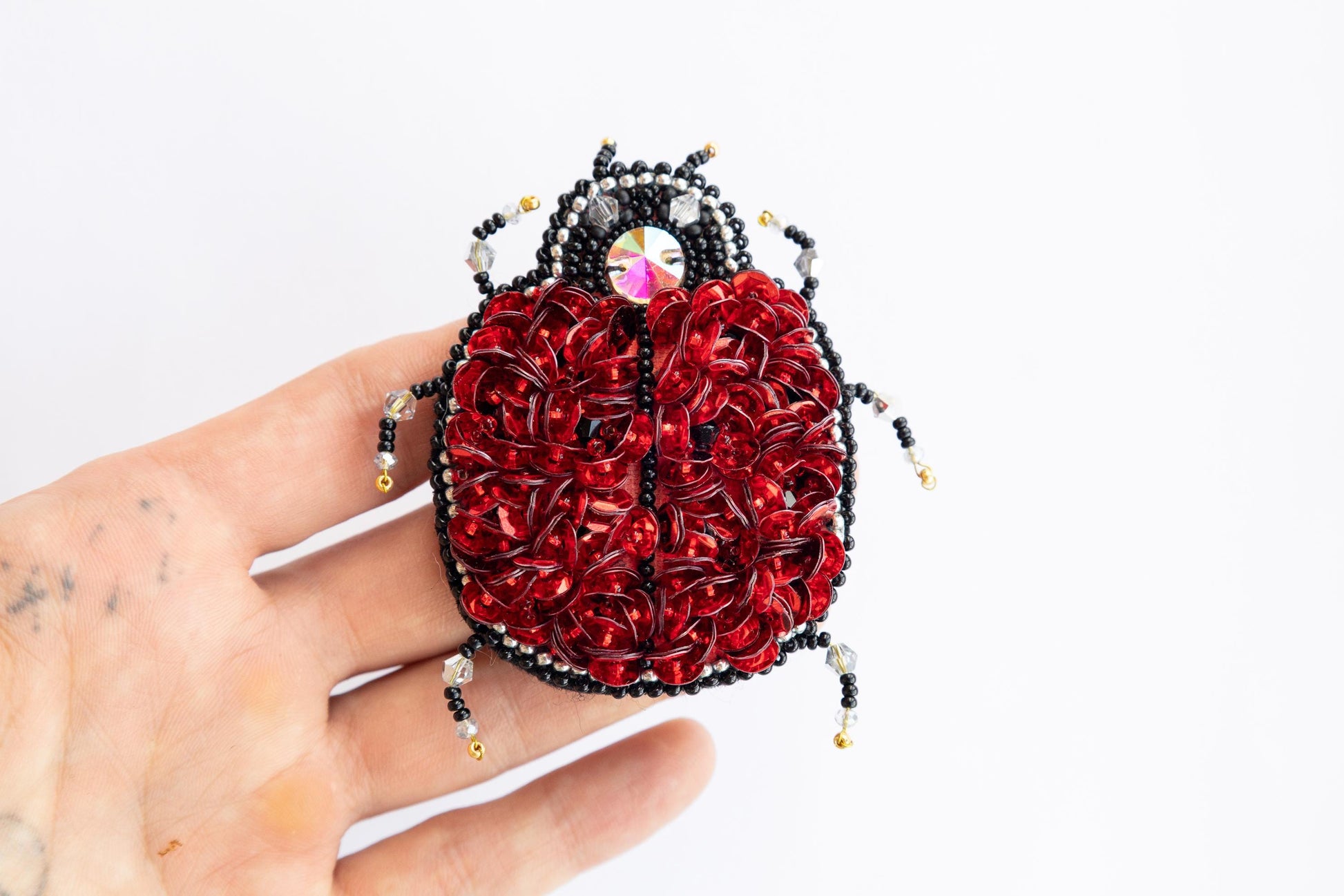 a hand holding a beaded red and black purse