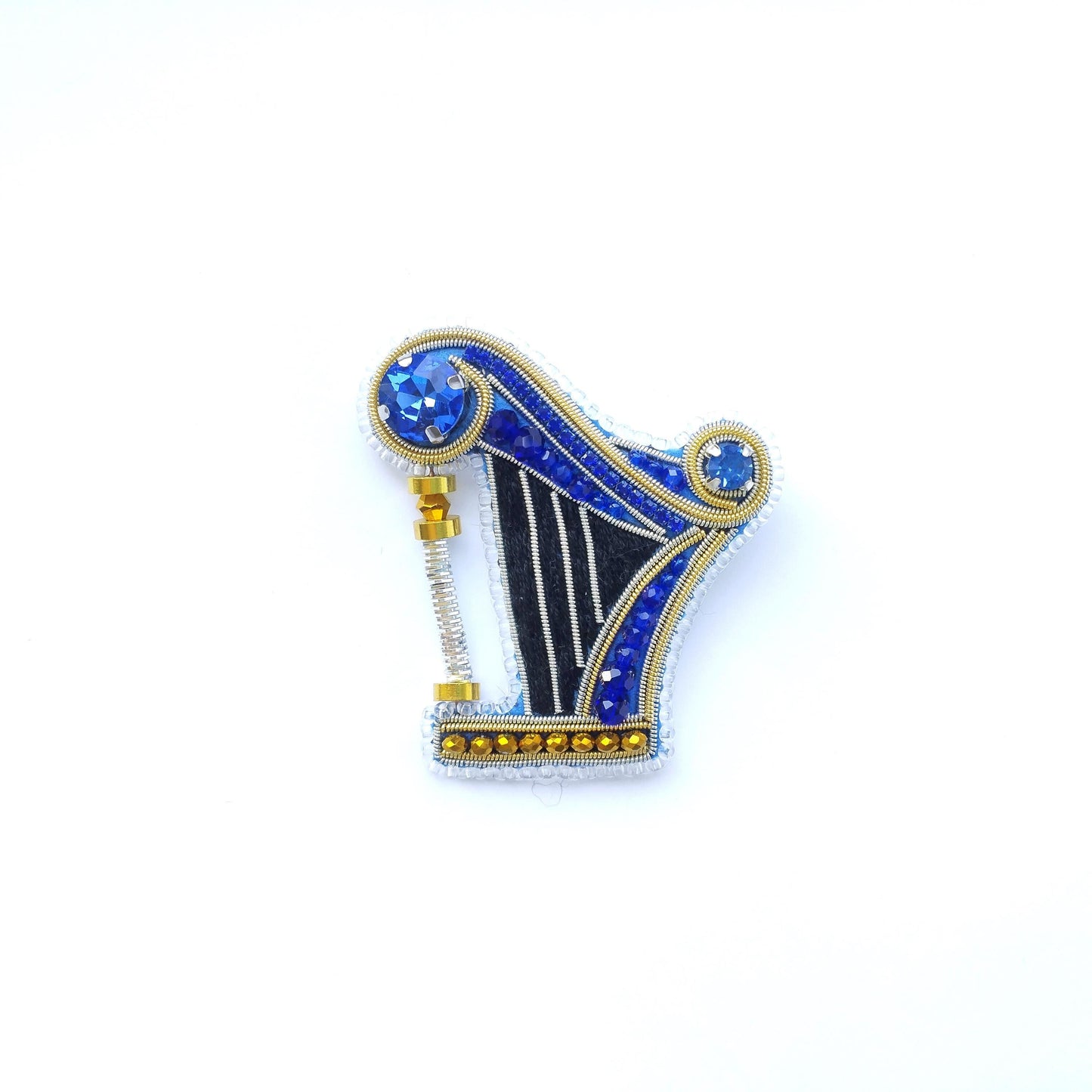 A decorative piece featuring a harp-shaped design with blue and gold elements, including gemstones.