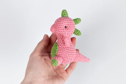 a hand holding a pink crocheted stuffed animal