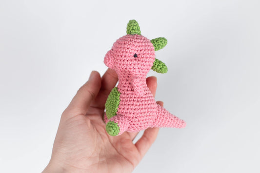 a hand holding a pink crocheted stuffed animal