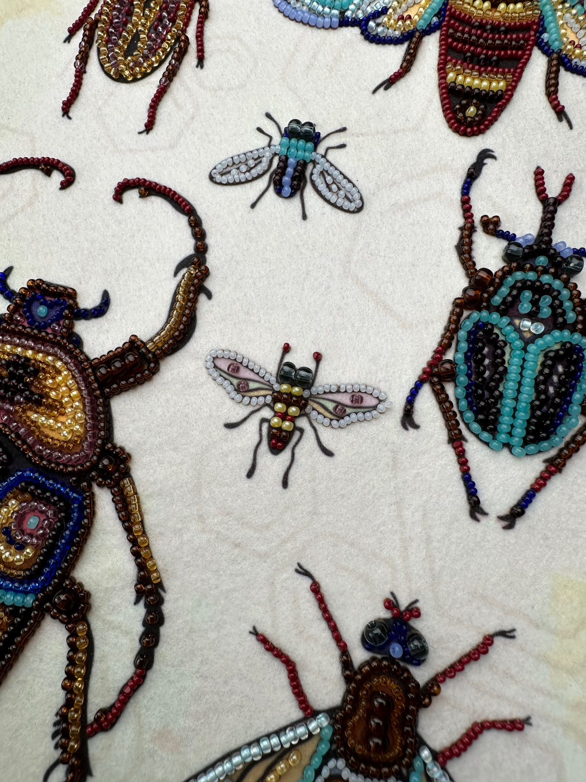 a close-up view of a collection of intricately designed insects, including a large dragonfly, a smaller bee, and several other colorful and detailed insects.