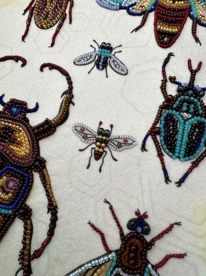 a close-up view of a collection of intricately designed insects, including a large dragonfly, a smaller bee, and several other colorful and detailed insects.