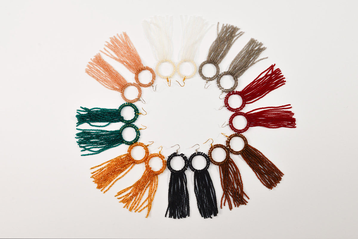A circular arrangement of various colorful tassel earrings with different colors and designs.