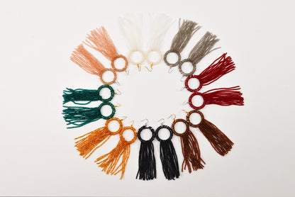 A circular arrangement of various colorful tassel earrings with different colors and designs.