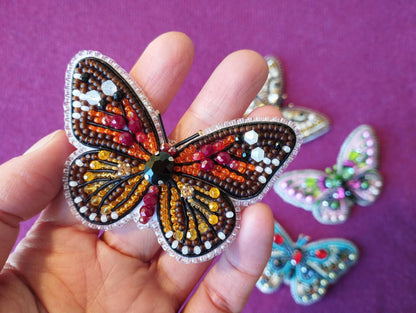 a hand holding a butterfly shaped brooch in it&#39;s palm