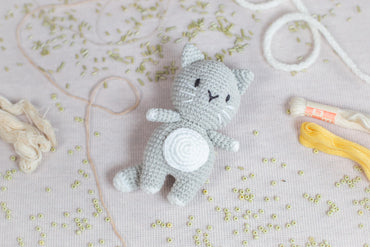 a crocheted cat sitting next to a pair of scissors