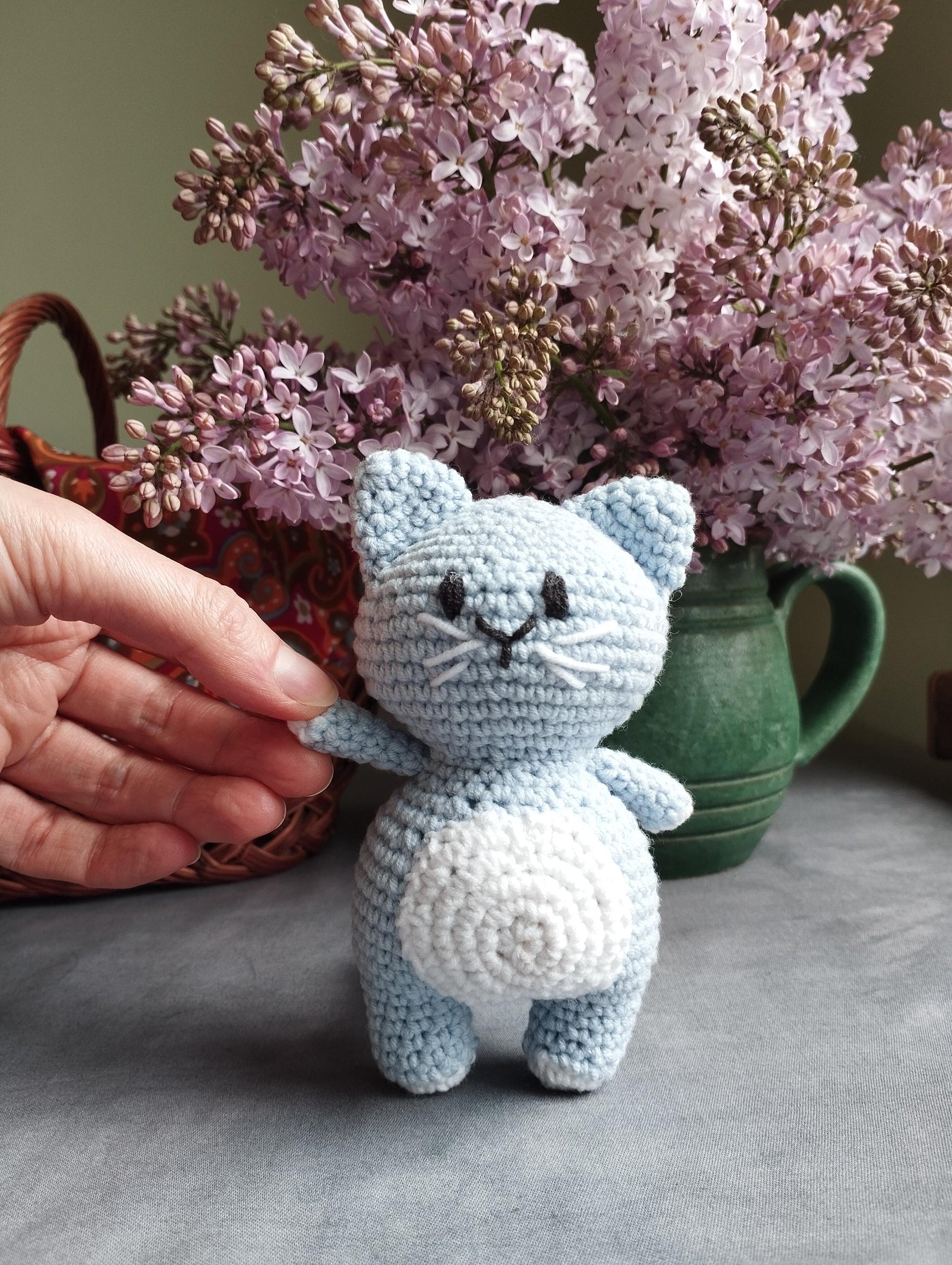 a crocheted cat sitting next to a vase of flowers