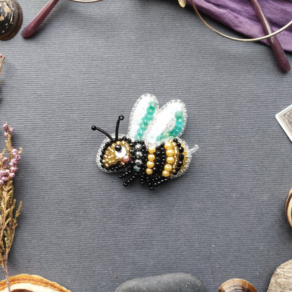 a detailed embroidered bee pin resting on a gray surface.