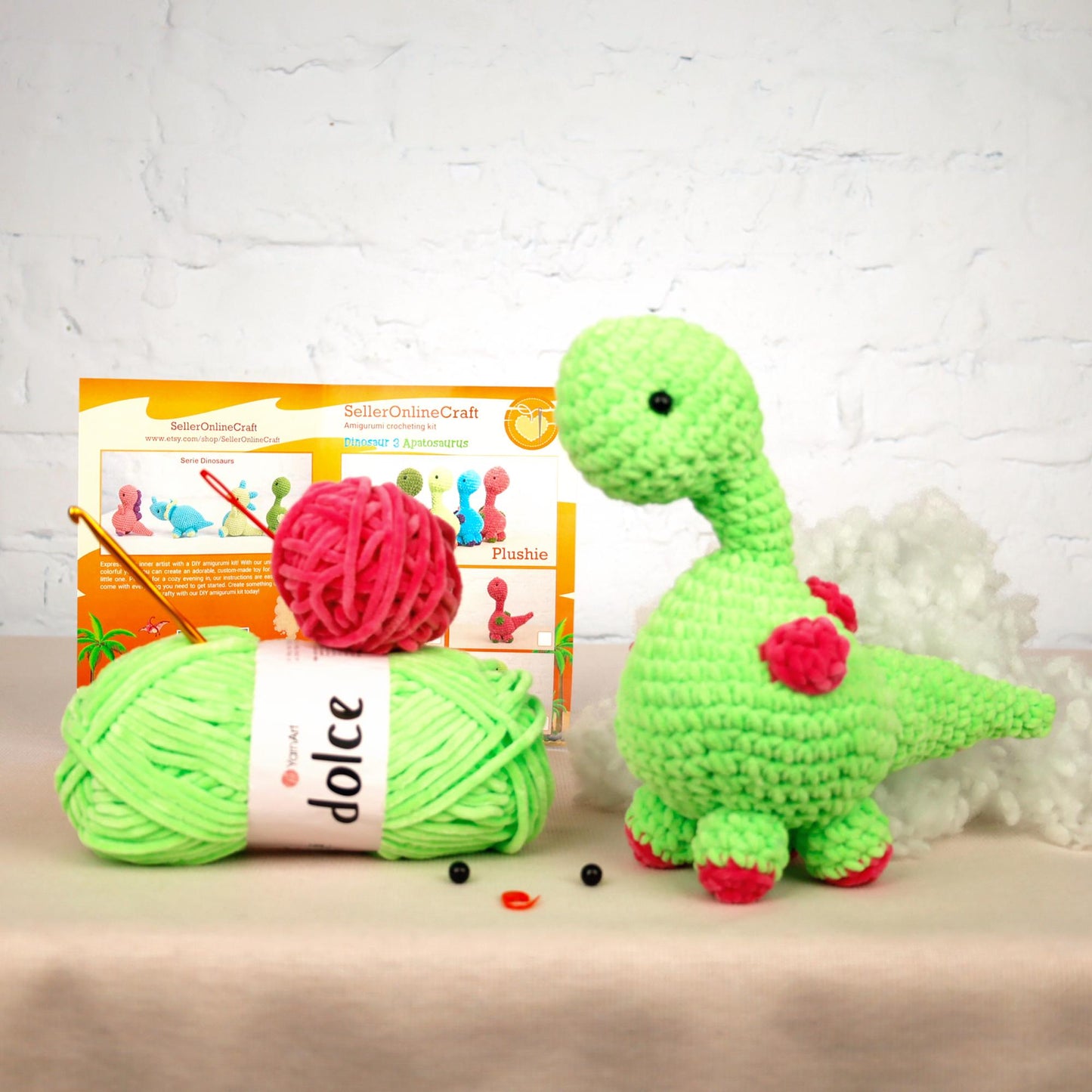 a green crochet dinosaur next to a ball of yarn