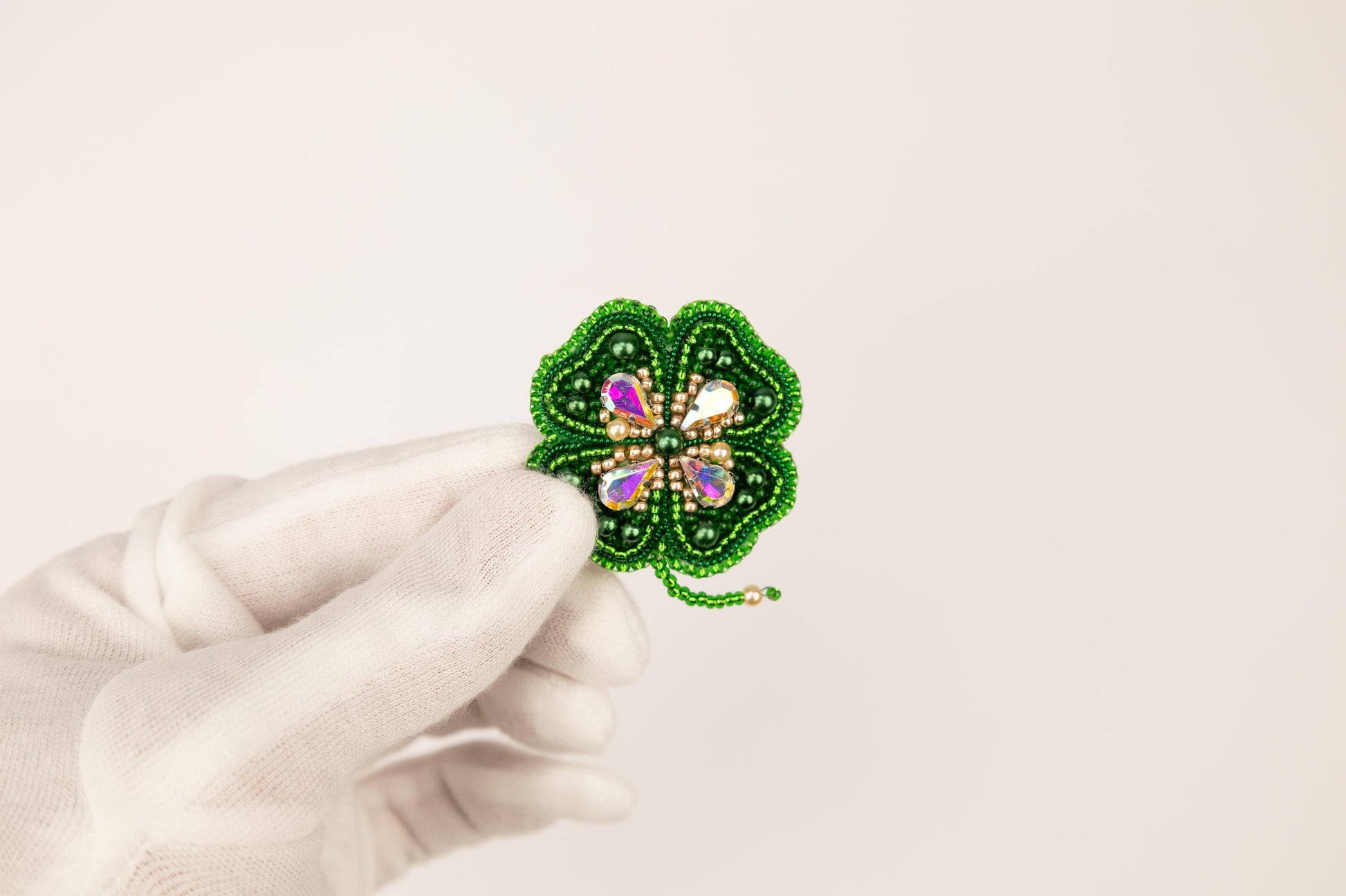 a person wearing a white glove holding a green brooch