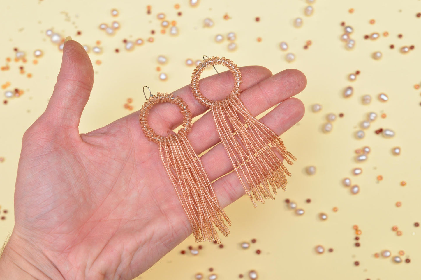 a hand holding a pair of gold earrings