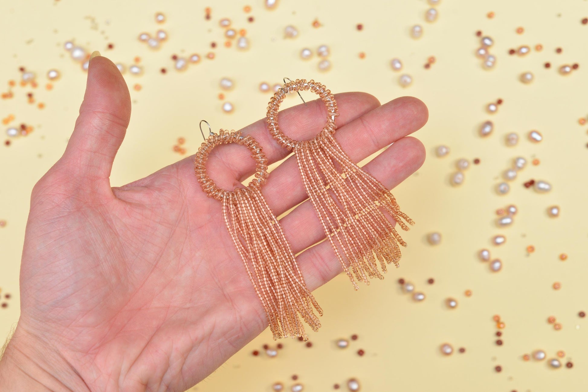 a hand holding a pair of gold earrings