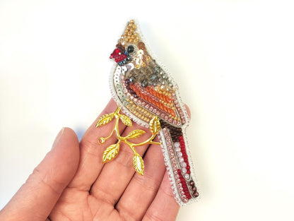 a small bird brooch sitting on a persons hand
