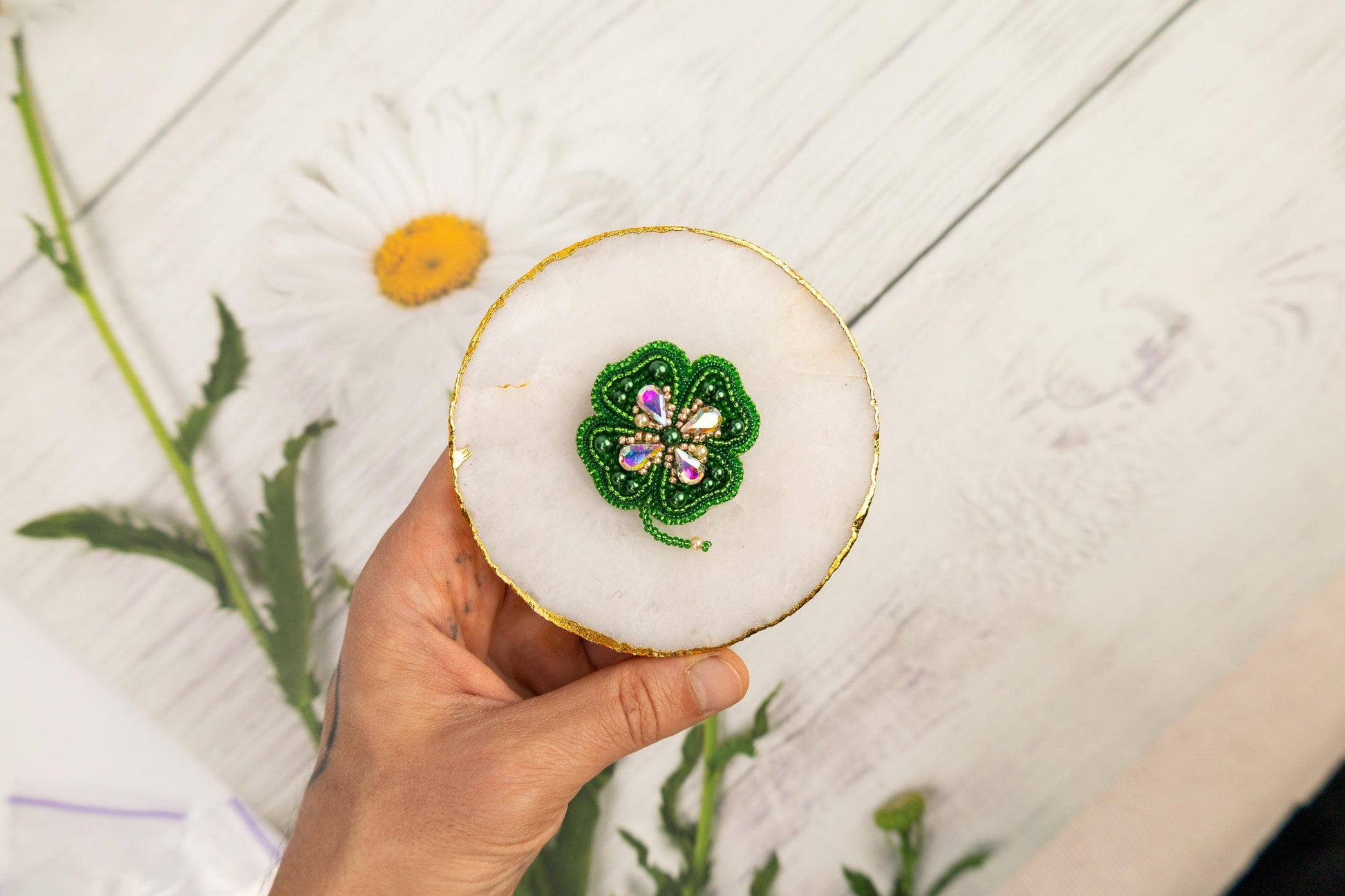 a person holding a small white object with a green flower on it