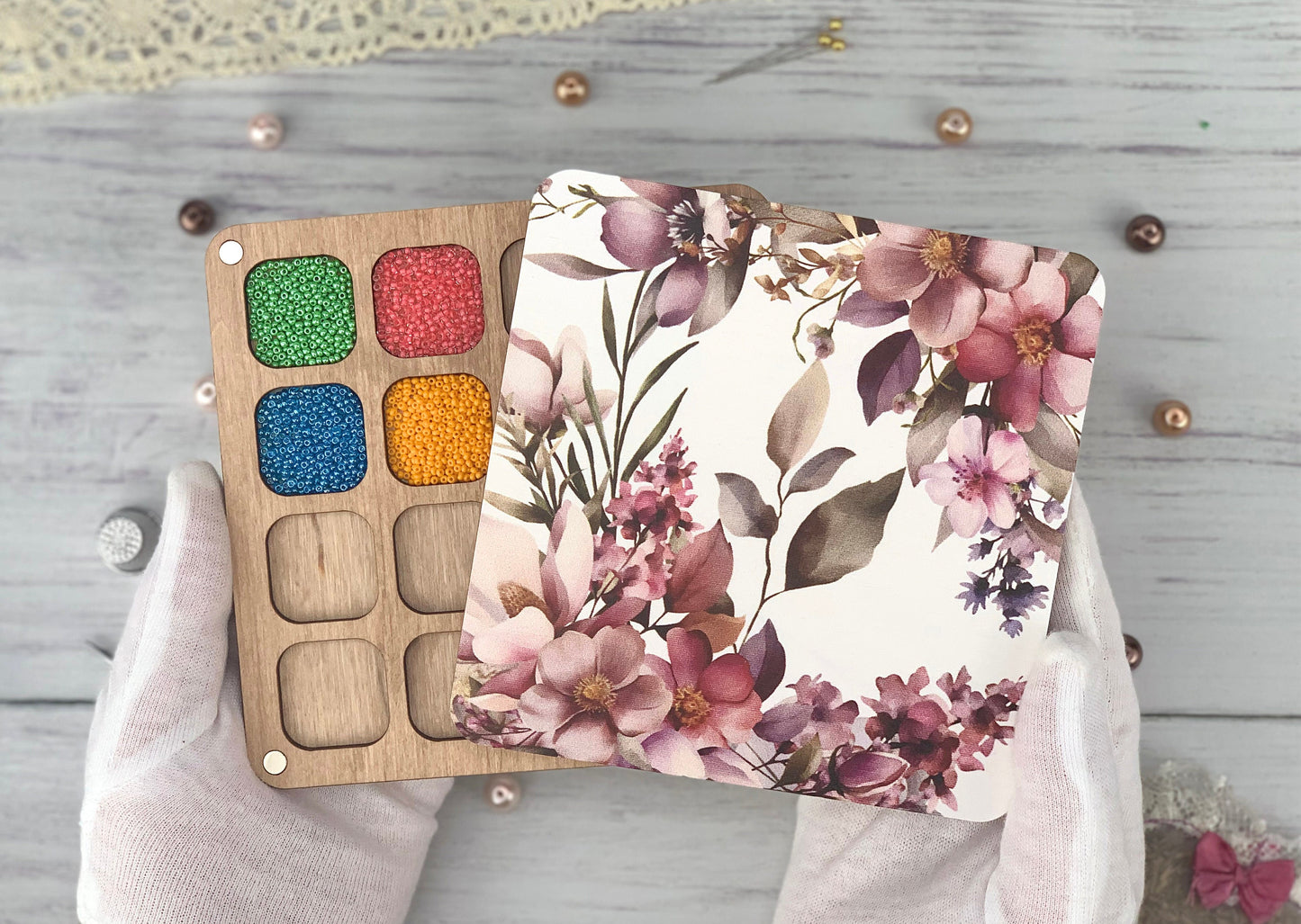 a person holding a wooden palette with flowers on it