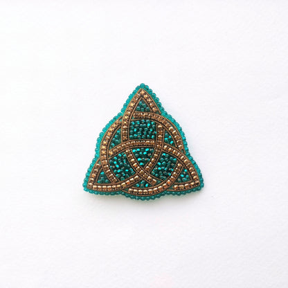 A triangular piece of jewelry with a beaded design, featuring a combination of blue and gold colors.