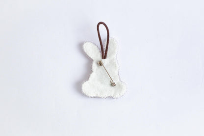 A white felt bunny shape with a brown string attached to it, placed against a plain white background.