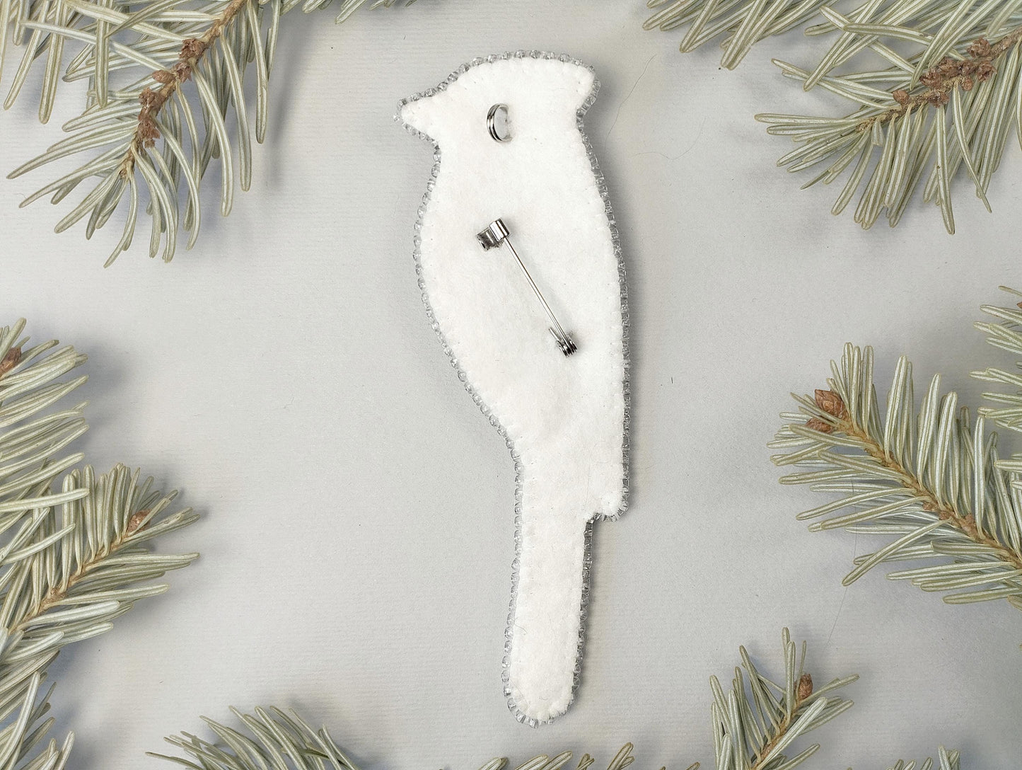 a white brooch sitting on top of a pine tree