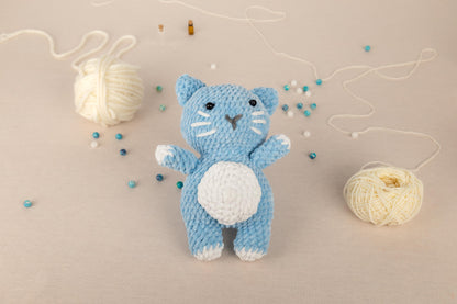 a crocheted cat is next to a ball of yarn