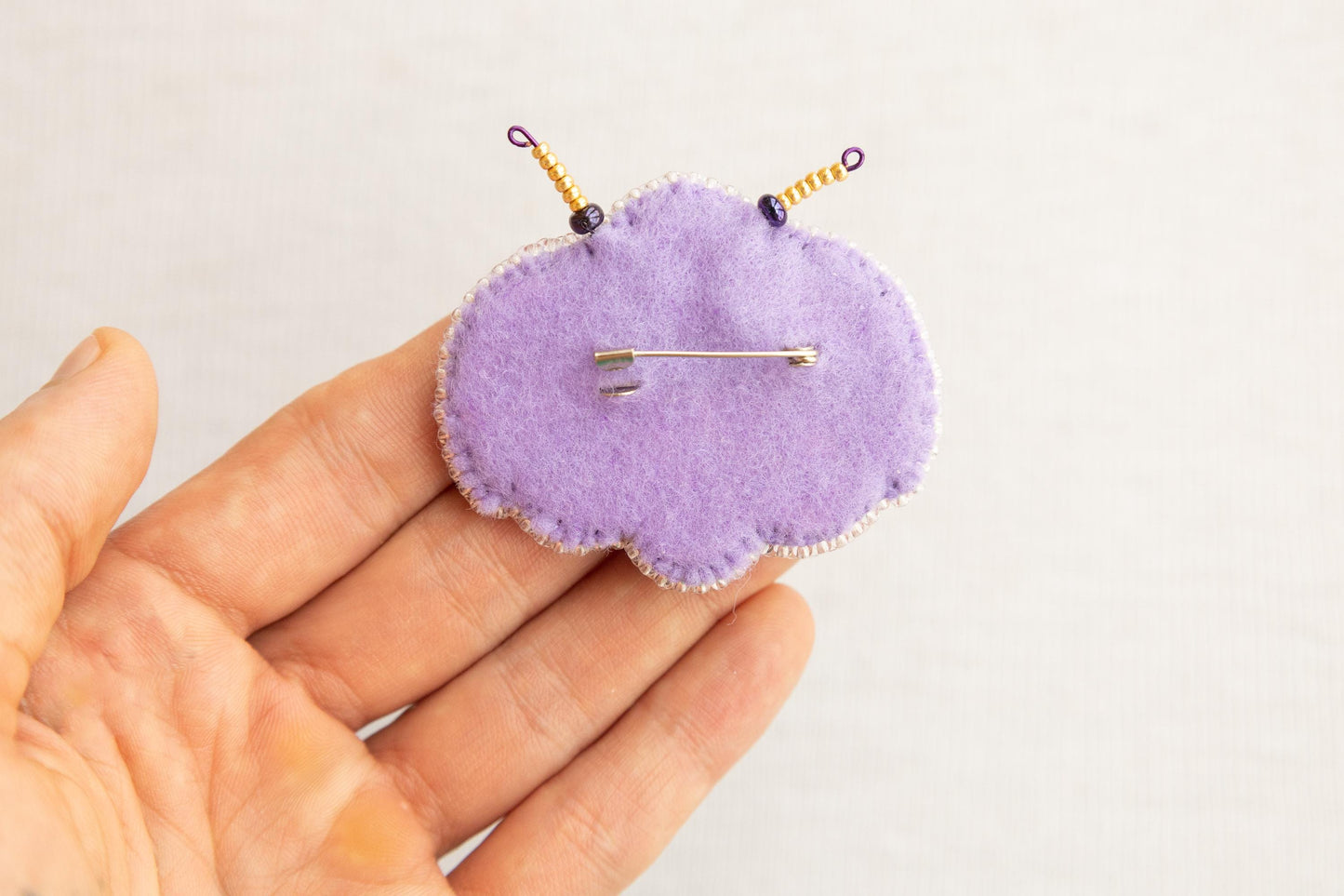 a hand holding a purple pin cushion with a needle