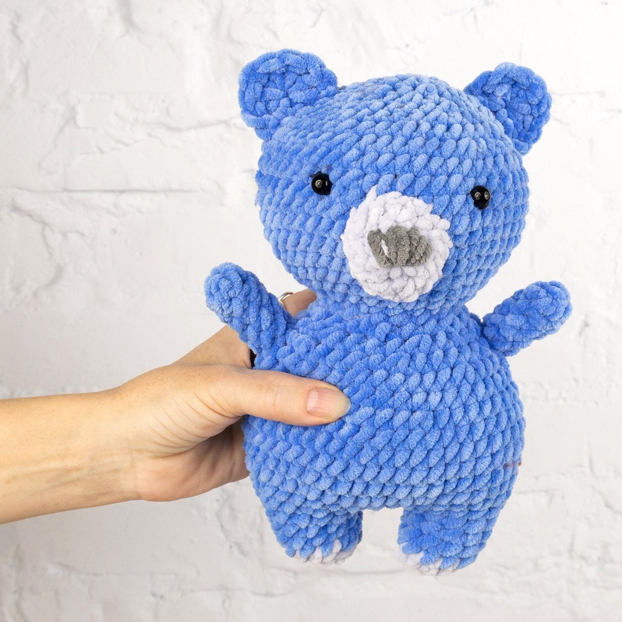 a blue knitted teddy bear standing on its hind legs