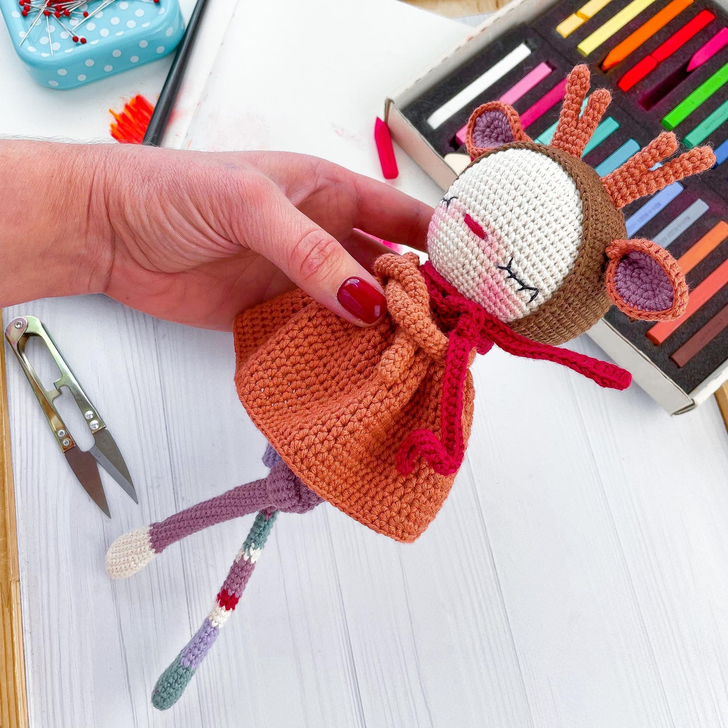 a hand holding a small doll on top of a table