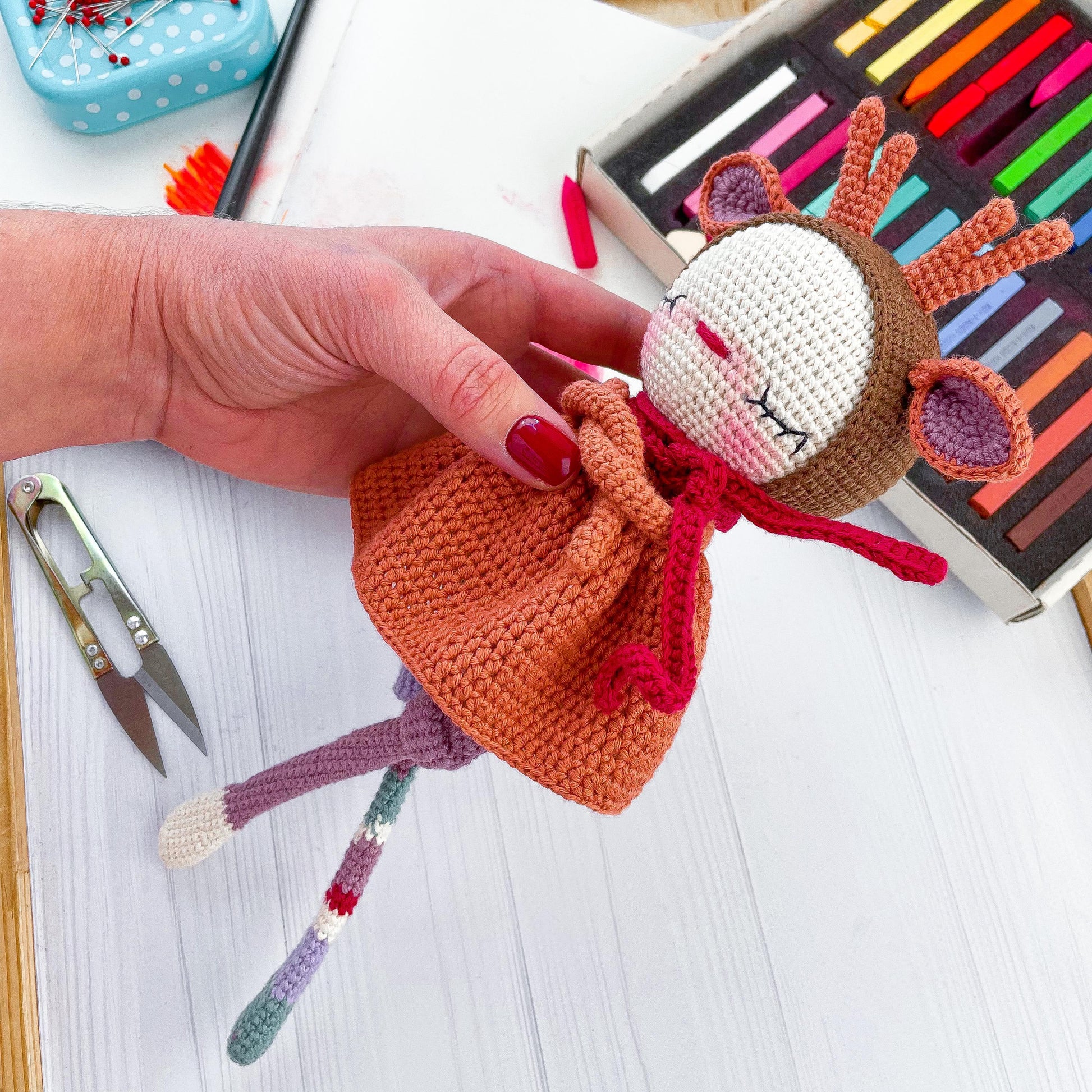 a hand holding a small doll on top of a table