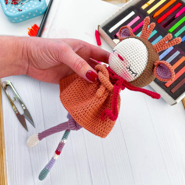 a hand holding a small doll on top of a table