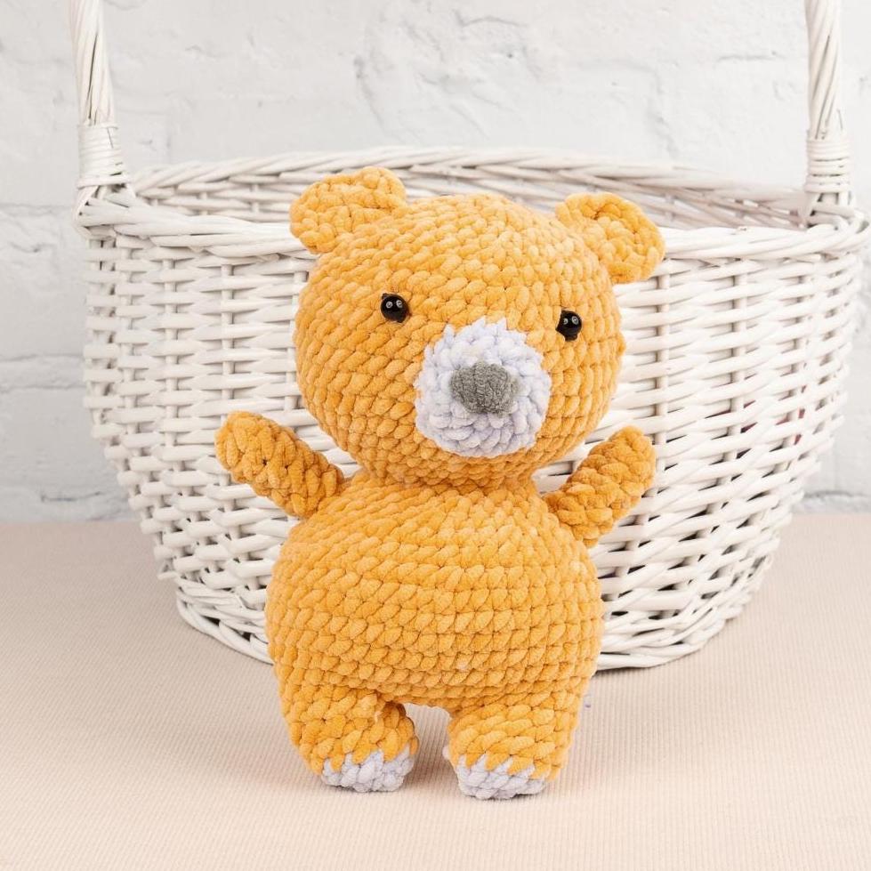 a teddy bear sitting next to a ball of yarn
