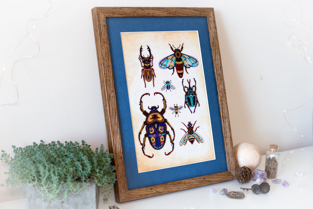 a framed illustration of various colorful insects, including a large beetle, a bee, and several other insects, displayed on a white surface.