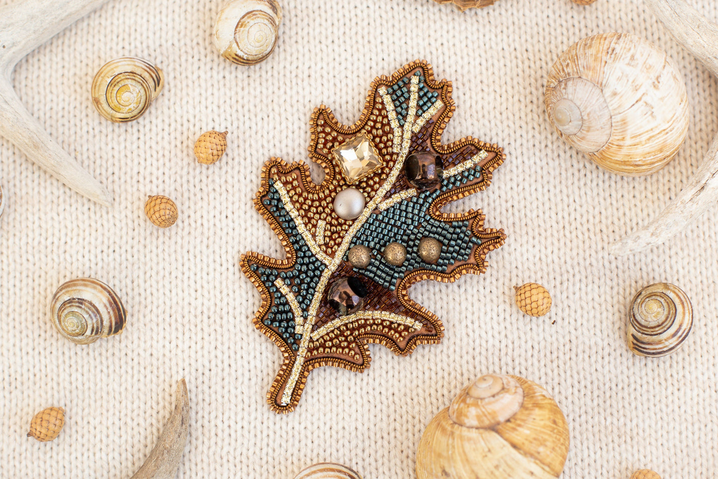 a close up of a brooch with a leaf on it