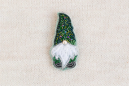 A decorative brooch in the shape of a gnome, made of colorful beads and a white beard.