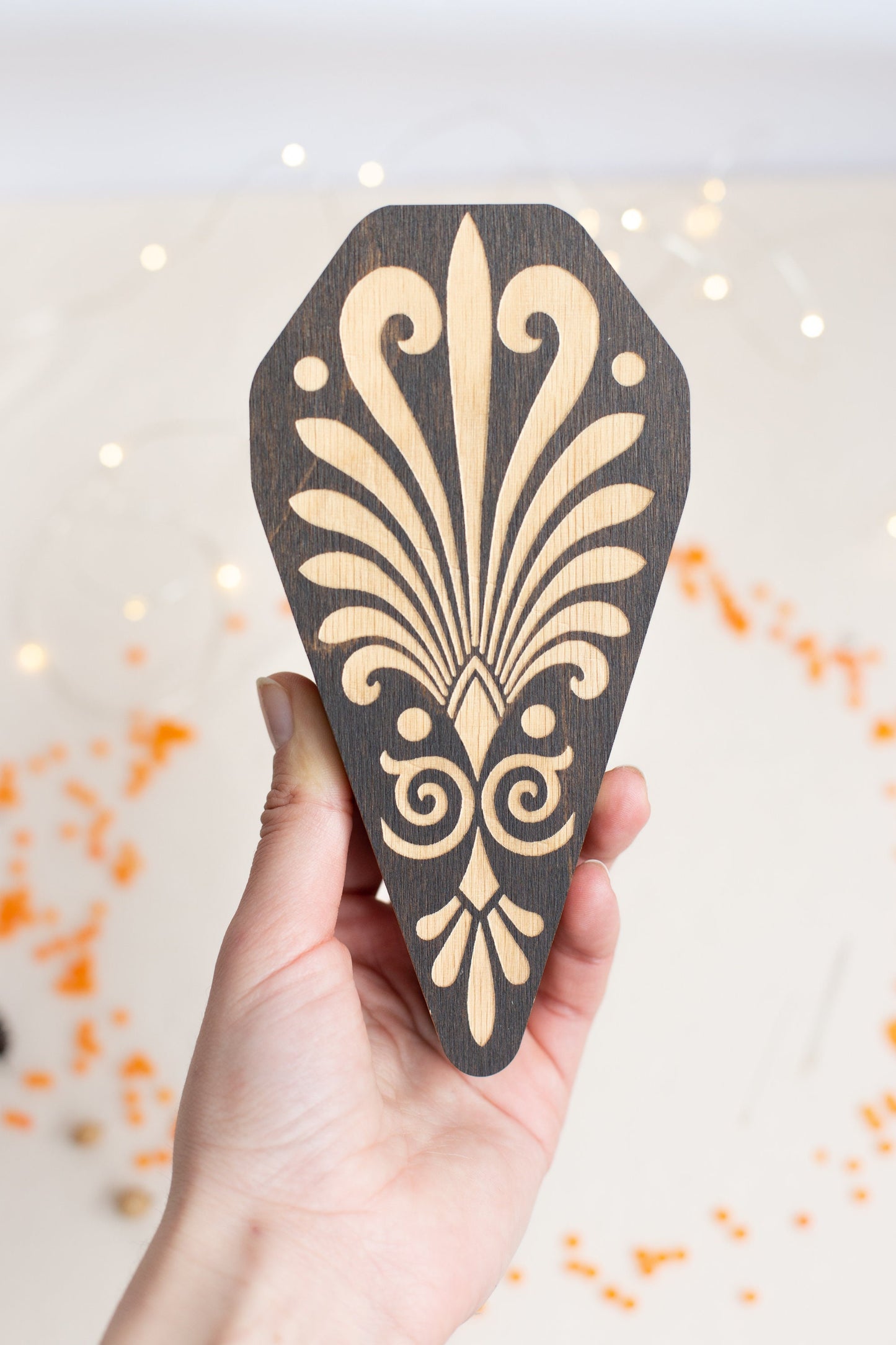 a hand holding a piece of wood with a design on it